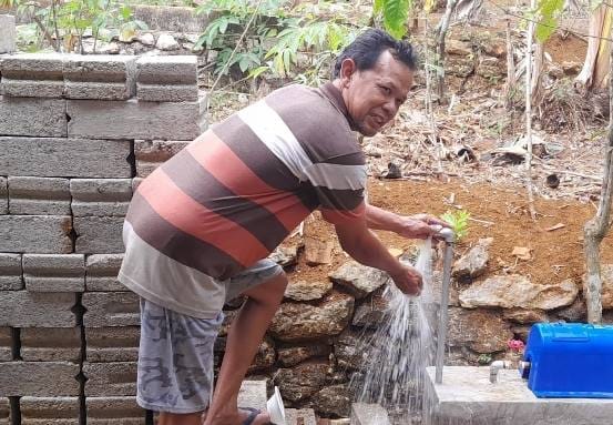 Ilustrasi warga menunjukkan sambungan air minum mengalir deras di sekitar rumahnya. (Foto : Istimewa).